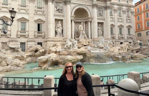 Visitors smile before Rome’s Trevi Fountain with its ornate marble sculptures and turquoise water.