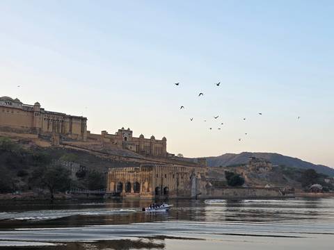 Amber Fort and Maota Lake with birds flying at dawn