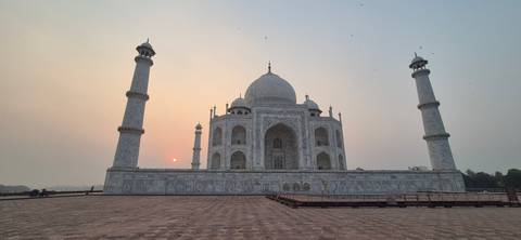 Iconic Taj Mahal with delicate sunrise light and a tiny sun orb beside the minaret.
