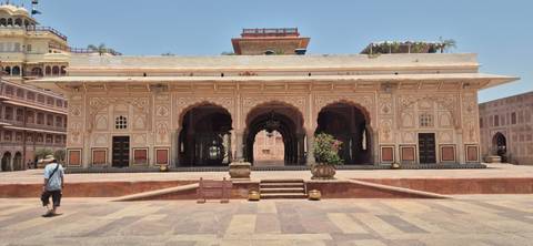 Intricately painted pavilion with arched entrances in an Indian palace courtyard under bright midday sun.