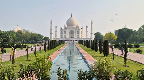 Classic frontal view of the Taj Mahal gardens with reflecting pool and visitors on pathways.