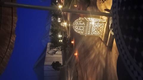 Lantern-lit paths wind between luxury desert tents beneath a dark starless sky.