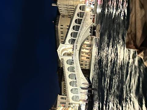 Night view of the Rialto Bridge and Grand Canal illuminated with reflections on water.