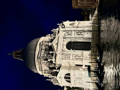Santa Maria della Salute basilica illuminated at night with gondola posts in foreground.