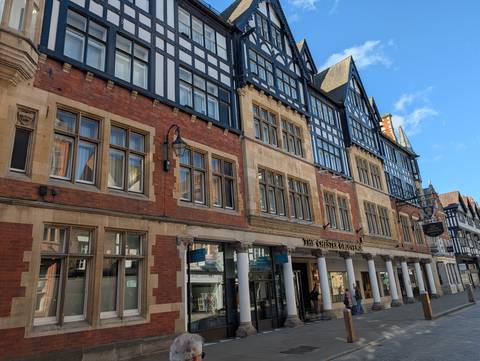 Historic Tudor-style timber and brick buildings on a commercial street in Chester.