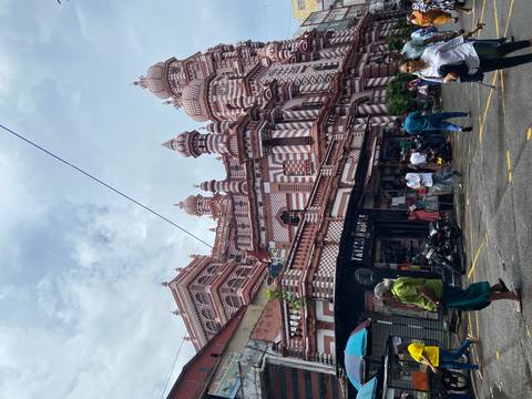 Red-and-white striped mosque façade with street activity in front under cloudy sky