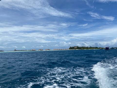 Deep-blue ocean with resort island of over-water villas under a bright sky