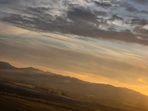 Moody sunset sky over distant mountain ridge with warm golden light