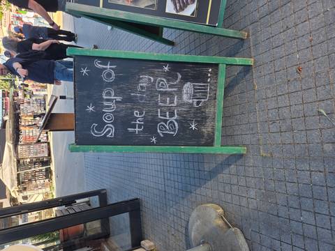 Humorous chalkboard on a city pavement reading 'Soup of the Day BEER'