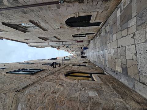 Narrow stone alleyway between tall limestone walls in an old town