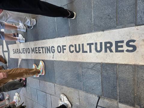 Pavement inscription marking 'Sarajevo Meeting of Cultures' with tourists’ feet around