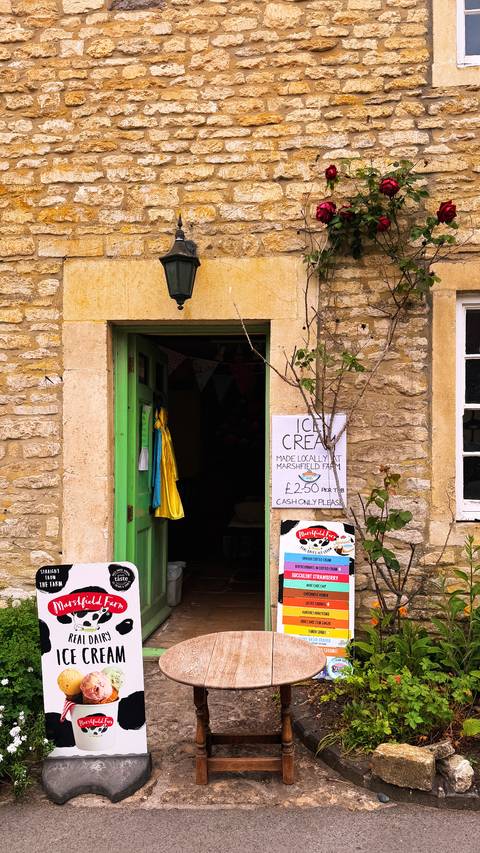 A stone storefront with bright green door advertises locally made ice cream with handwritten signs.