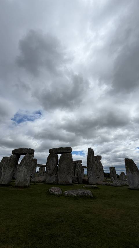 Massive prehistoric stones of Stonehenge stand silhouetted against a dramatic cloudy sky.