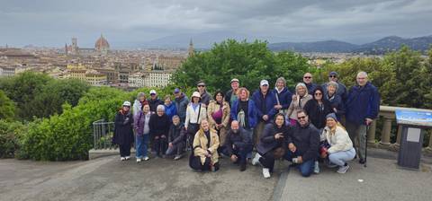 Large tour group poses on a viewpoint above Florence with the Duomo and cityscape spread below.