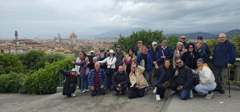 Tour participants cheer and gesture while overlooking Florence’s terracotta rooftops and famous dome.