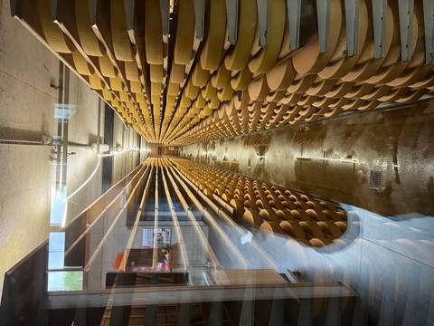 Long corridor stacked floor-to-ceiling with aging cheese wheels inside a production cellar.