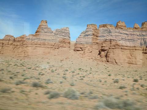Blurred view from a moving vehicle of rugged desert mesas and sandstone towers.