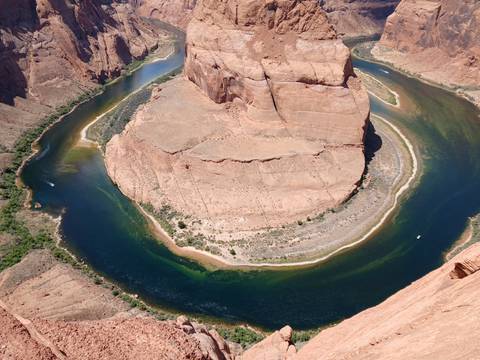 Overhead view of the dramatic horseshoe bend of a deep blue river curving around a sandstone mesa.