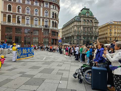 Street demonstration in a historic European square bordered by ornate buildings and onlookers with luggage.