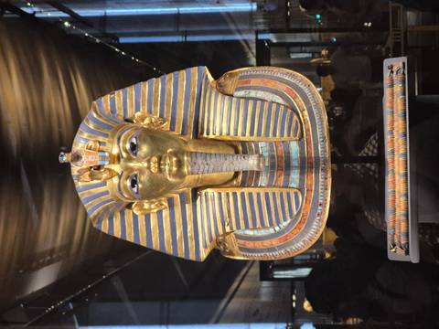 Close-up of Tutankhamun's golden funerary mask displayed under dramatic lighting.