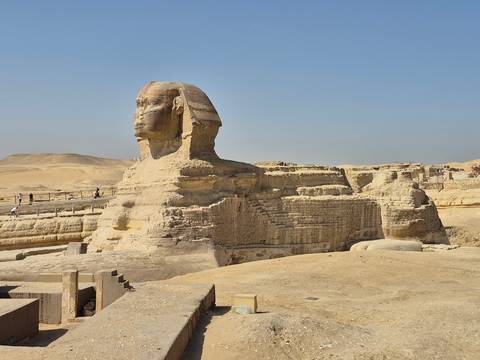 Side profile of the Great Sphinx with its monumental limestone body against a clear sky.