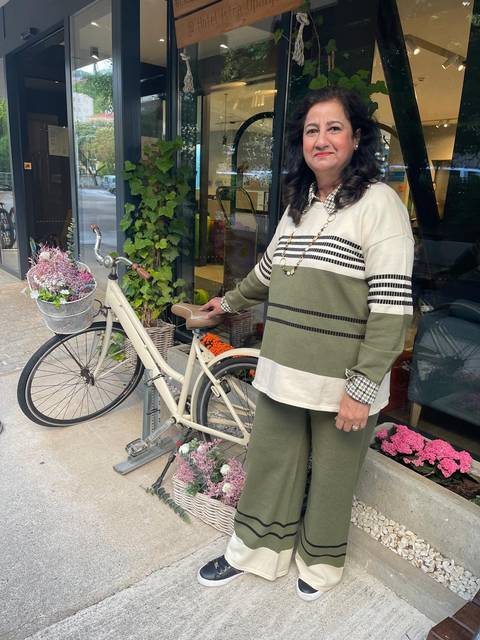 Traveller poses beside a vintage cream bicycle adorned with fresh flowers outside a chic café