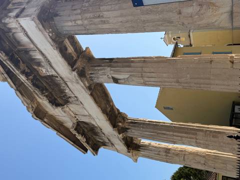 Ancient marble gateway with towering columns against a clear blue Athens sky.