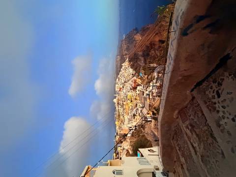 Wide view of Santorini’s cliff-side town glowing with early morning light above the Aegean Sea.
