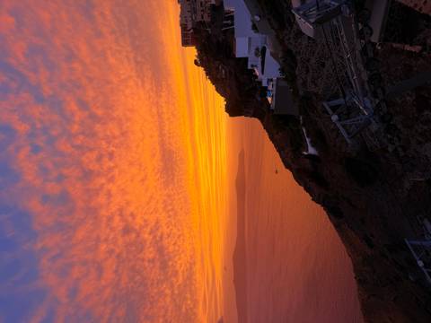 Dramatic orange and pink sunset sky over the sea and coastal cliffs.