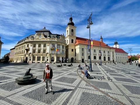 The grand baroque buildings of Sibiu’s Great Square stand over patterned cobblestones and strolling visitors.