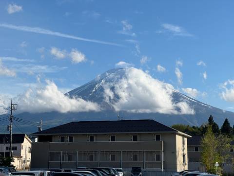 Snow-capped Mount Fuji emerging through clouds above suburban rooftops