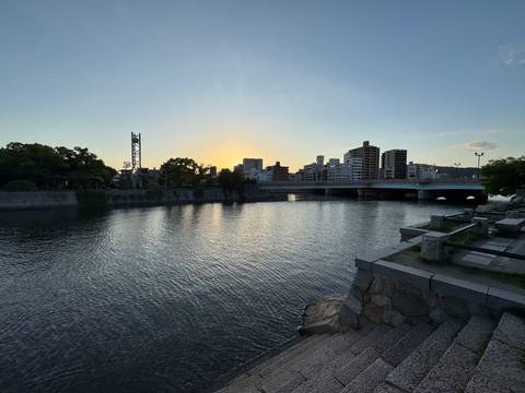 River in Hiroshima at dusk with bridge and city skyline against setting sun