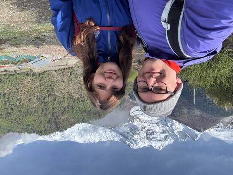 Selfie of couple in trekking gear with snowy mountains behind