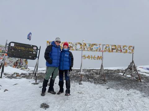 Hikers posing at snowy 5416m Thorong La Pass sign
