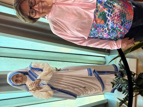 Wax figure of Mother Teresa next to partially visible visitor inside museum.