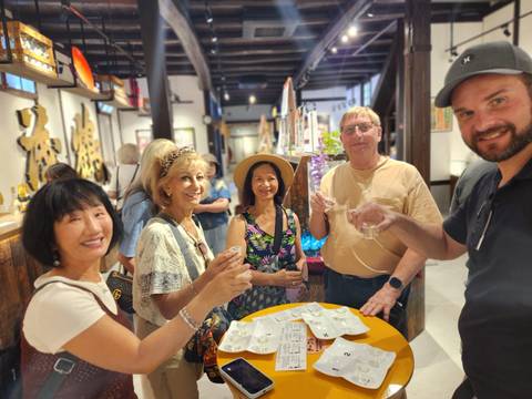 Tour group raising sake cups inside Japanese brewery shop.