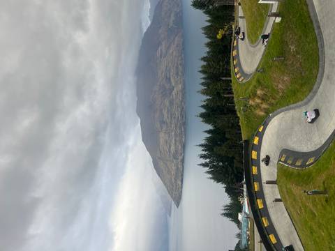 Winding luge track descending green hillside overlooking lake and forest in Queenstown