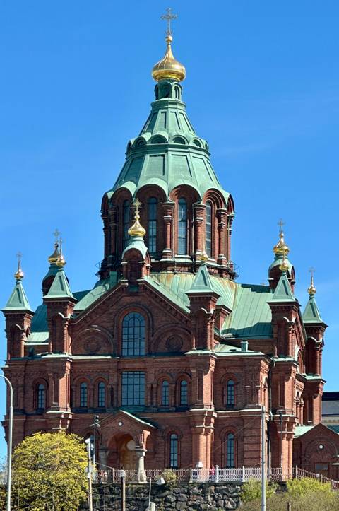 Close-up of red-brick Uspenski Cathedral crowned with green copper domes and golden crosses