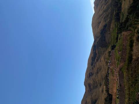 Low stone terraces and rolling hills sit beneath a vast blue sky in the Andean highlands.