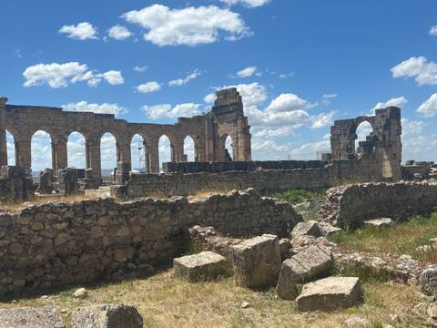 Stone arches and columns of ancient Roman ruins rise against a bright blue sky at Volubilis.
