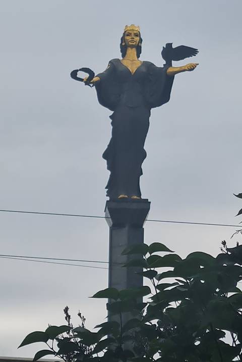 Blurry distant silhouette of a tall monument against a grey overcast sky.
