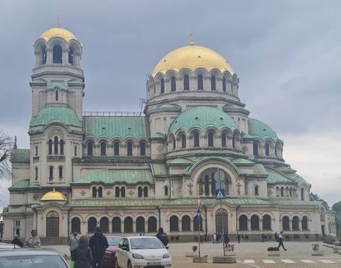 Grand Orthodox cathedral with green copper domes and gilded accents beneath an overcast sky.