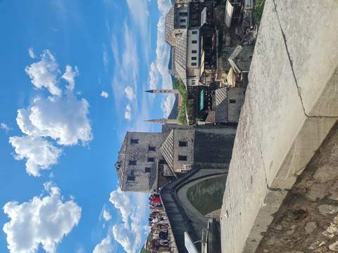Panoramic view toward Mostar’s medieval arched Stari Most bridge and stone old town under bright blue skies.