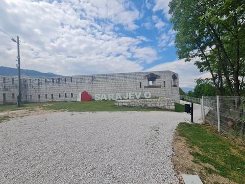 "I ♥ Sarajevo" sign mounted on a cement wall at a historic fort on a bright cloudy day.