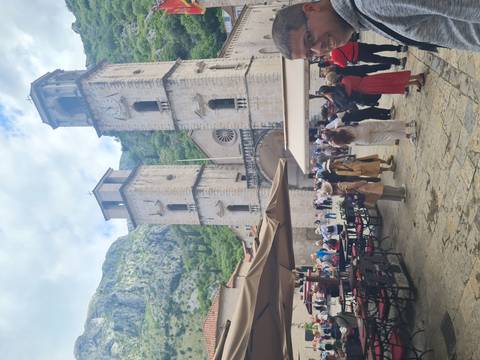 Bustling square with outdoor cafés facing the twin-towered Cathedral of Saint Tryphon framed by green mountains.