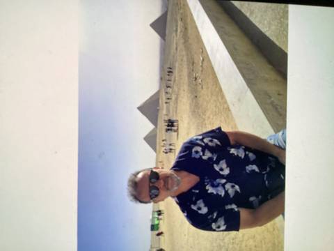 Man in sunglasses poses with the Great Pyramids of Giza rising in the hazy background.