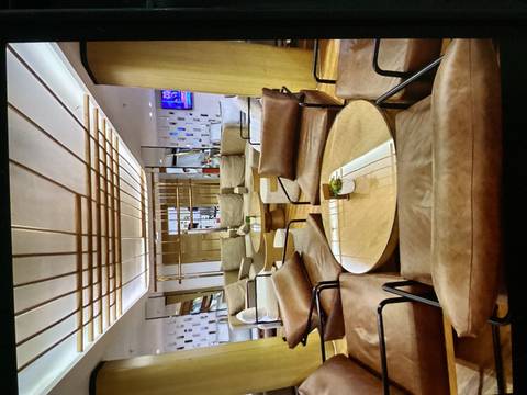 Modern lounge area with tan leather chairs and a sleek wooden coffee table under geometric ceiling lights.