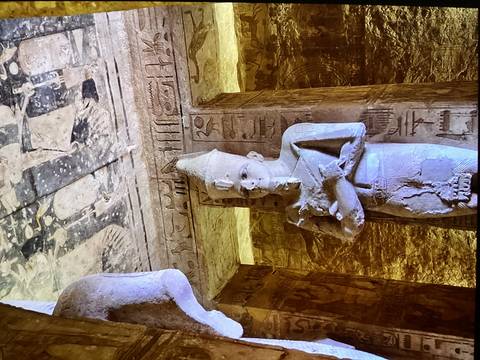 Interior chamber of Abu Simbel with standing pharaoh statue lit by warm light and detailed hieroglyphics.