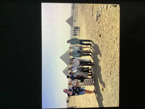 Tour group poses together on the Giza Plateau with three pyramids in the distance.