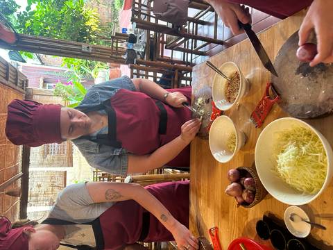 Participant in a red apron finely chops ingredients during a Vietnamese cooking class.